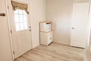 Doorway with wood finished floors and baseboards