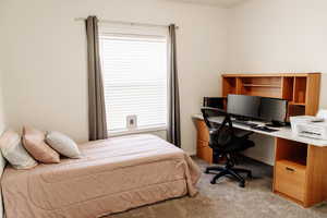 Bedroom featuring light colored carpet and a desk