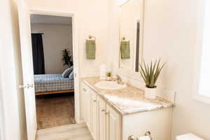 Half bath featuring vanity, light wood-style flooring, and connected bathroom