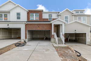 View of front of house with concrete driveway, an attached garage, board and batten siding, and brick siding