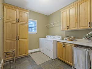 Laundry area with cabinet space, separate washer and dryer, and dark stone finish flooring