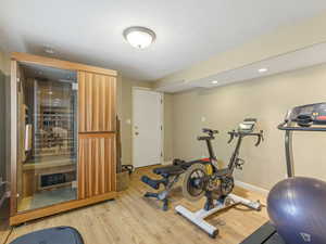 Exercise room with light wood-style floors, recessed lighting and separate entrance
