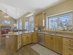 Kitchen with stainless steel appliances, wood finished floors, light stone counters, and light brown cabinetry