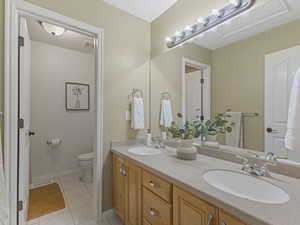 Full bath with light tile patterned floors and double vanity