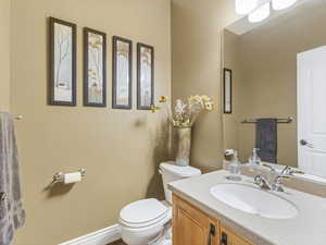 Main floor half bathroom featuring vanity and toilet