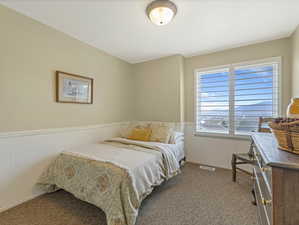 Carpeted bedroom featuring a wainscoted wall