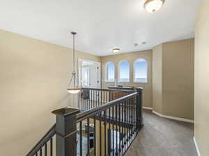 Hallway featuring an upstairs landing and light carpet