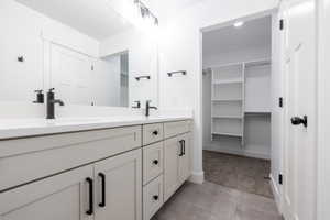 Bathroom with double vanity, light carpet, and a spacious closet
