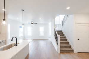 Kitchen with light wood-style flooring, plenty of natural light, hanging light fixtures, and light stone countertops