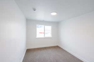Carpeted spare room featuring baseboards and a smoke detector