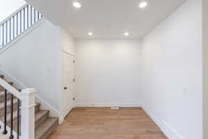 Stairway featuring wood finished floors and recessed lighting