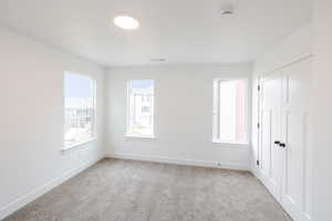 Unfurnished bedroom featuring light colored carpet, a closet, and multiple windows