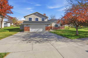 Traditional-style home with brick siding, a front lawn, concrete driveway, and roof with shingles
