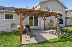 Rear view of property featuring a pergola, a yard, a patio area, and a storage shed