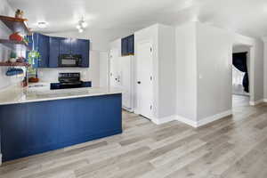 Kitchen featuring blue cabinetry, open shelves, light Granite countertops, 2 pantries, and lofted ceiling