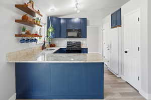 Kitchen with blue cabinets, open shelves, a peninsula, light countertops