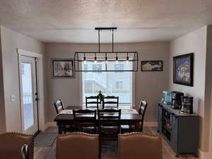 Dining area featuring plenty of natural light, wood finished floors, and a textured ceiling