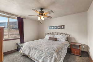 Carpeted bedroom featuring a textured ceiling and a ceiling fan