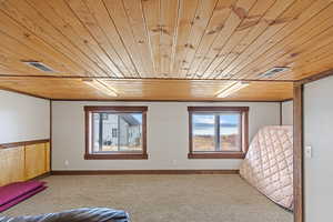Unfurnished bedroom featuring wooden ceiling and carpet