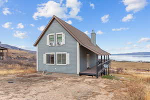 View of side of home featuring a chimney and a deck with water view
