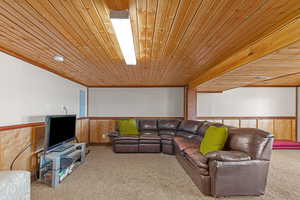 Carpeted living room featuring wainscoting, wood ceiling, and wood walls