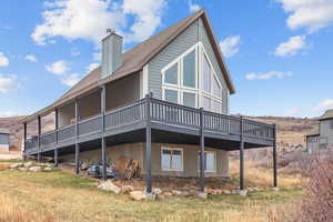 Back of house featuring a wooden deck, a shingled roof, and a chimney