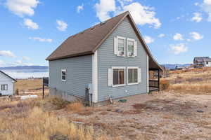 View of side of property featuring roof with shingles and a water and mountain view