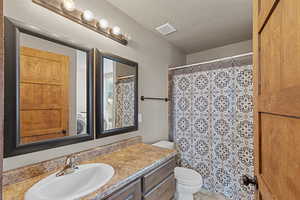 Full bath featuring vanity, a shower with shower curtain, and a textured ceiling
