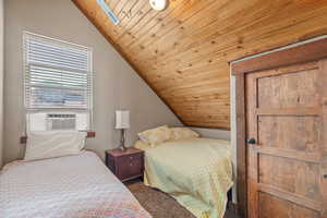 Bedroom featuring wood ceiling, vaulted ceiling, a skylight, and carpet