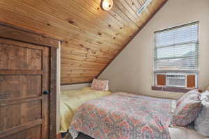 Bedroom with wooden ceiling, vaulted ceiling, and a skylight