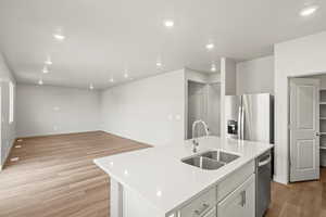 Kitchen featuring light wood-style flooring, recessed lighting, an island with sink, stainless steel fridge with ice dispenser, and open floor plan