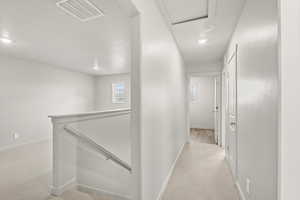 Hallway featuring an upstairs landing, light carpet, and recessed lighting