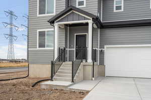 Entrance to property featuring an attached garage and concrete driveway