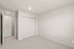 Unfurnished bedroom featuring light colored carpet and a closet