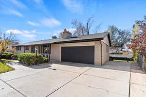 Ranch-style home with concrete driveway, brick siding, a chimney, and a garage