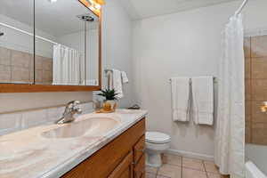 Full bathroom featuring light tile patterned floors, vanity, shower / bathtub combination with curtain, and a textured ceiling