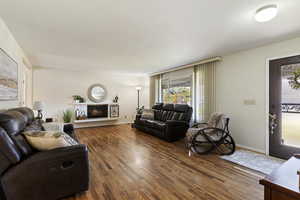 Living room with a lit fireplace and wood finished floors