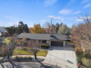 View of front of property featuring concrete driveway, a garage, and roof with shingles