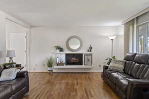 Living area with a lit fireplace and wood finished floors