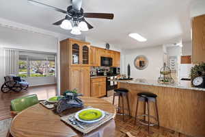 Kitchen with stainless steel electric range oven, glass insert cabinets, a breakfast bar area, light stone countertops, and black microwave