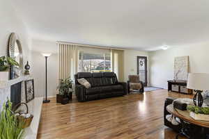 Living area featuring wood finished floors, healthy amount of natural light, and a fireplace with raised hearth