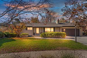 Ranch-style home featuring a chimney, brick siding, and a front yard