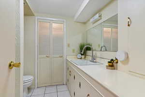 Bathroom with light tile patterned floors, a closet, and vanity