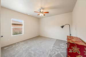 Unfurnished room featuring light carpet, a textured ceiling, and a ceiling fan