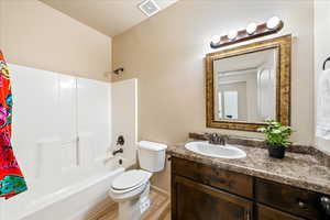Bathroom with vanity, shower / bath combo, and light wood-style flooring
