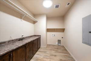 Laundry area with electric panel, light wood-style floors, hookup for a washing machine, and hookup for an electric dryer