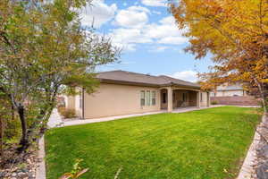 Rear view of property featuring stucco siding, a patio area, and a tiled roof