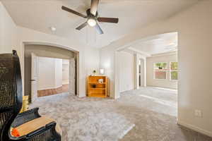 Bedroom featuring light carpet, arched walkways, and ceiling fan