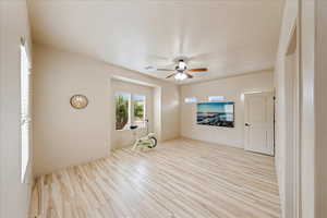 Unfurnished living room featuring light wood-style floors and a ceiling fan