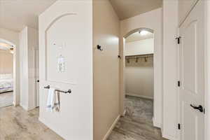 Hallway featuring arched walkways and light wood-type flooring